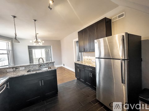 A modern kitchen with a stainless steel refrigerator and black cabinets.