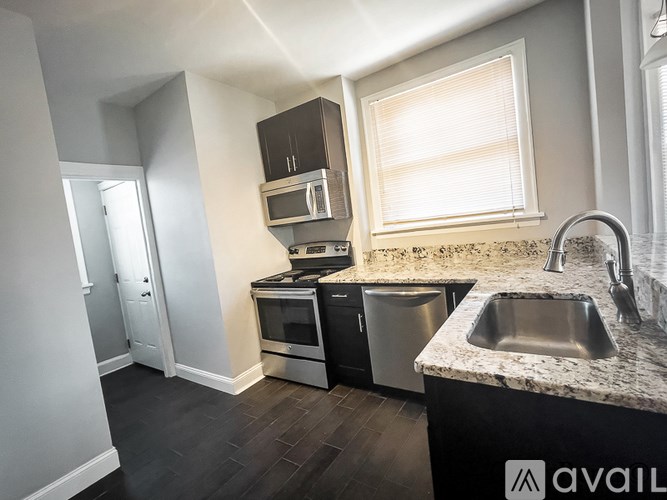 A kitchen with a sink, stove, and microwave.
