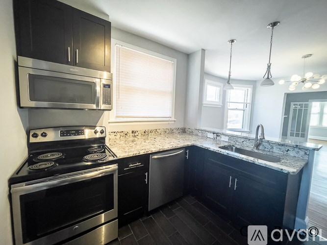 A modern kitchen with black cabinets and stainless steel appliances.