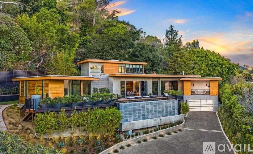 A modern house with a large front yard and a driveway leading to the garage.