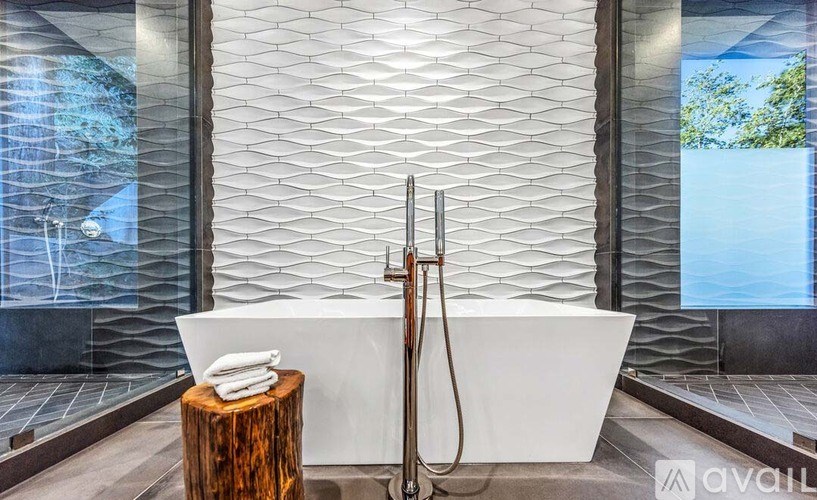 A modern bathroom with a white bathtub and a wooden stump on a stand.