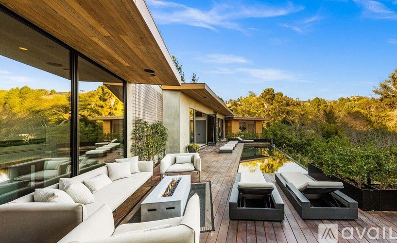 A modern outdoor living space with a wooden deck and white furniture.