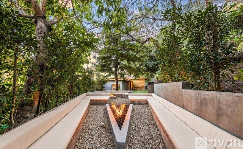 A modern garden with a gravel pathway and a fire pit in the middle.
