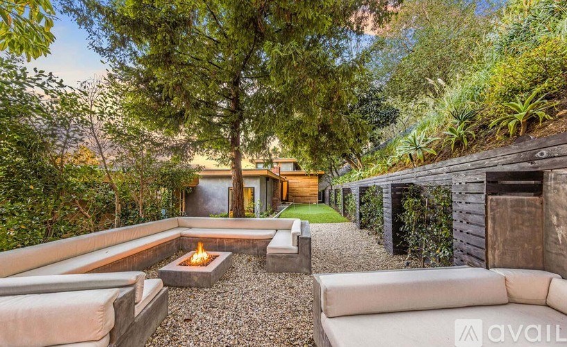 A modern backyard with a fire pit and seating area.