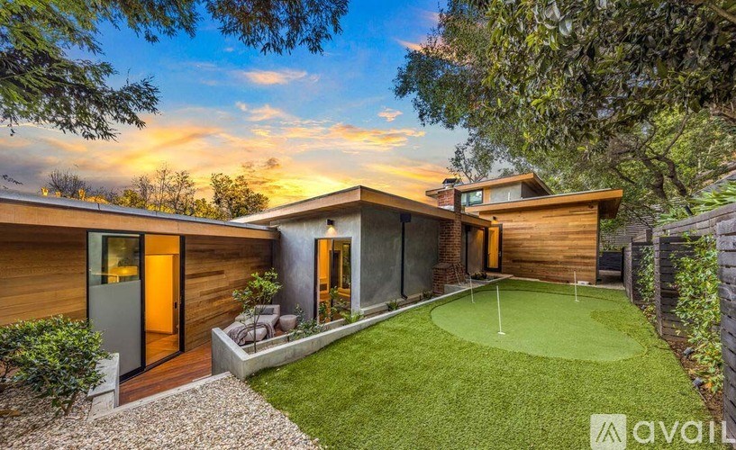 A modern house with a green lawn and a small putting green in the backyard.