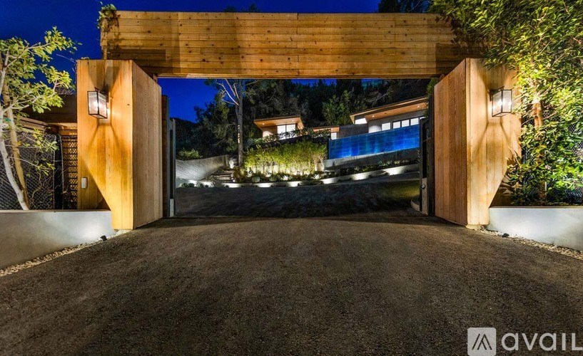 A modern house entrance with a wooden gate and lights on.