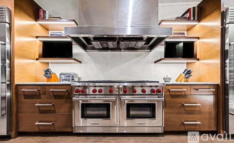 A kitchen with a stainless steel range hood and ovens.