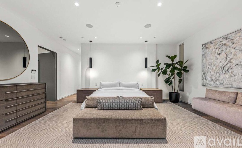 A bedroom with a large bed, a couch, and a plant.