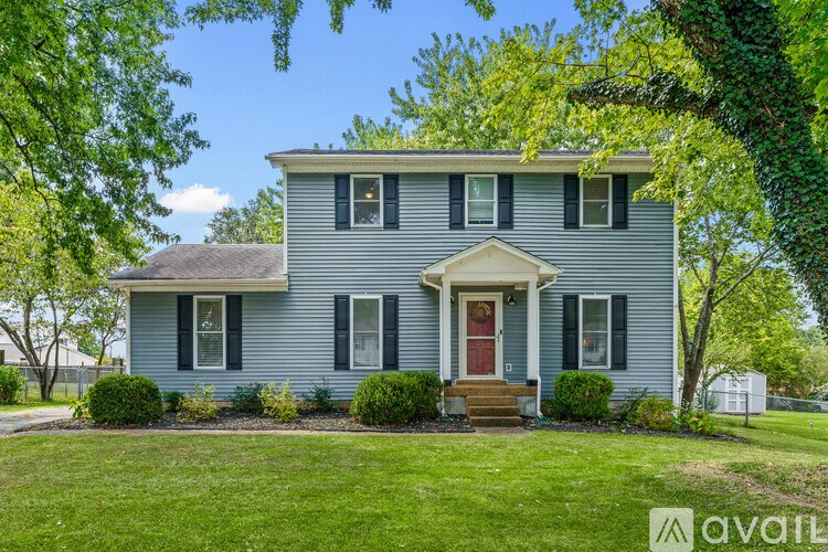 A house with a red door and green shutters is for sale.