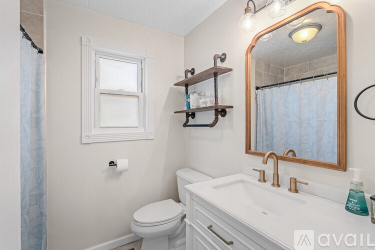 A bathroom with a toilet, sink, mirror, and shelves.