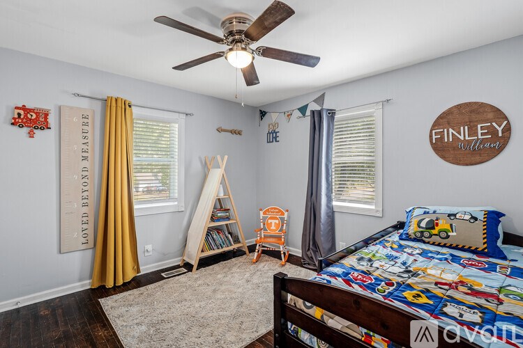 A child's bedroom with a bed, a fan, and a wall hanging that says "FINLEY WILLARD".