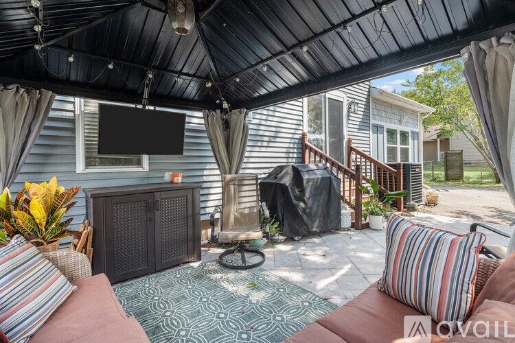 A patio with a black awning and a television mounted on the wall.