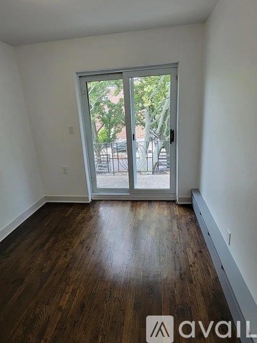 A room with wooden floors and a sliding glass door leading outside.