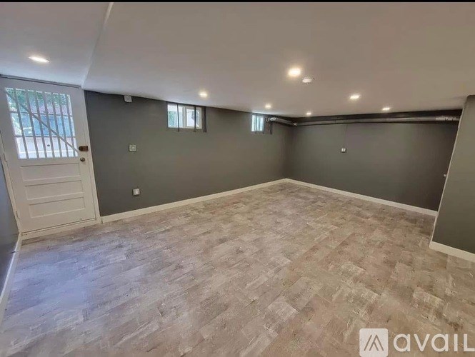 A spacious room with wooden flooring and grey walls.