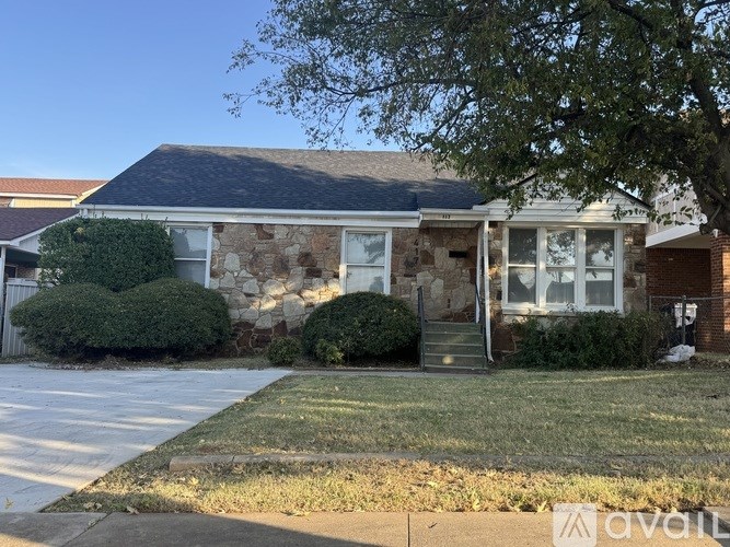 A house with a stone facade and a tree in front.