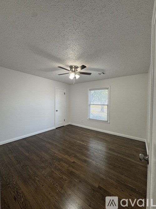 A room with a ceiling fan and wooden flooring.