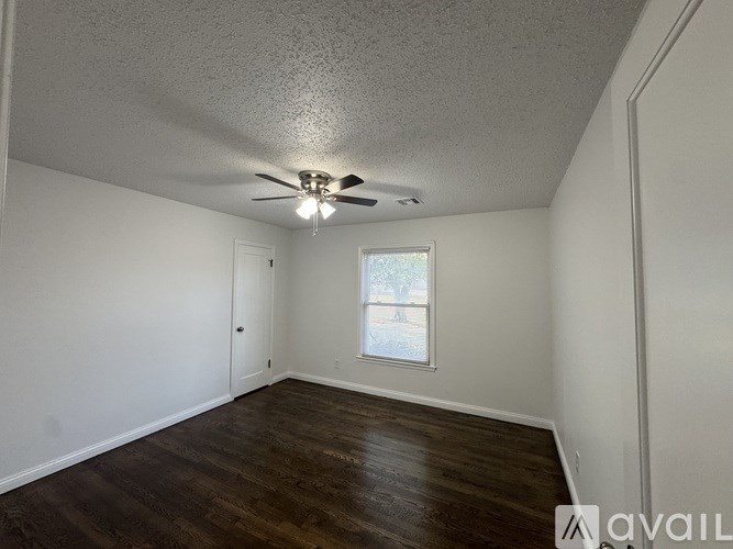 A room with a ceiling fan and wooden flooring.