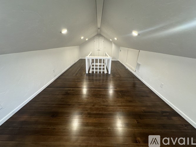 A room with wooden flooring and white walls.