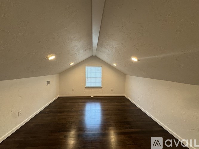 A room with wooden floors and a window in the middle.