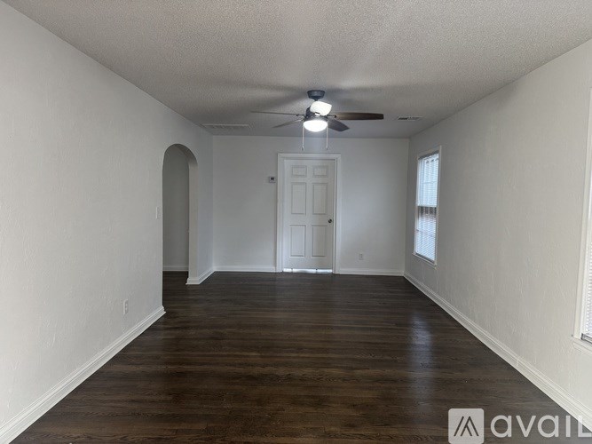 A spacious room with wooden floors and white walls.