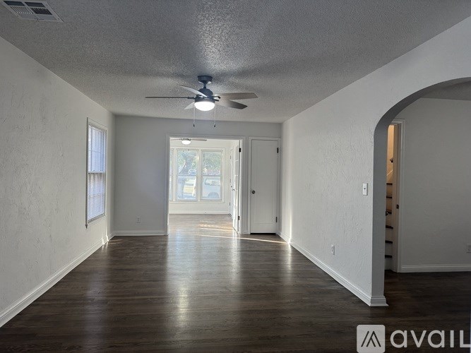 A spacious room with a ceiling fan and wooden flooring.