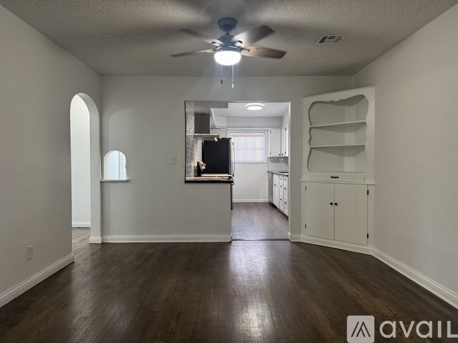 A spacious room with a ceiling fan and wooden flooring.