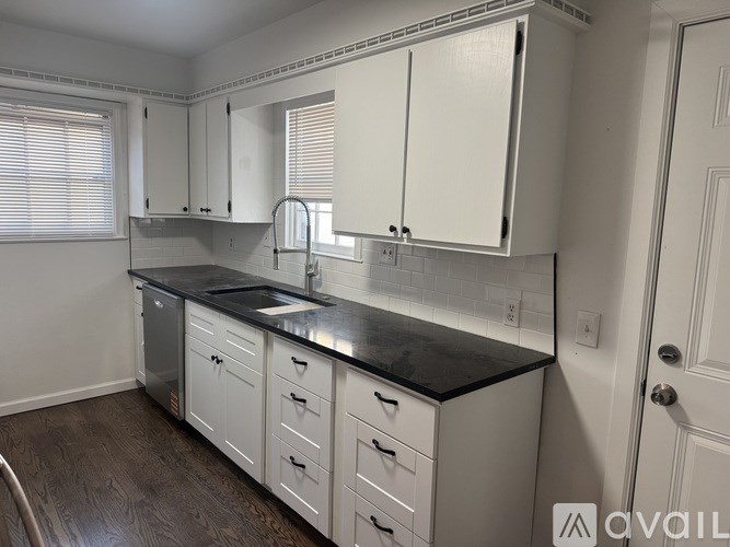 A kitchen with white cabinets and a black countertop.