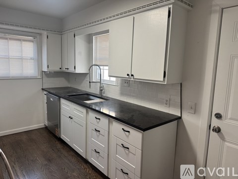 A kitchen with white cabinets and a black countertop.