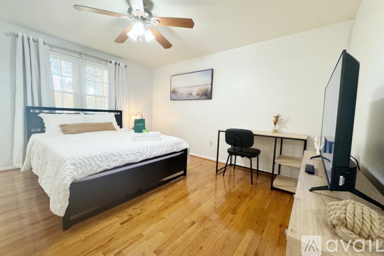 A bedroom with a bed, chair, and television.