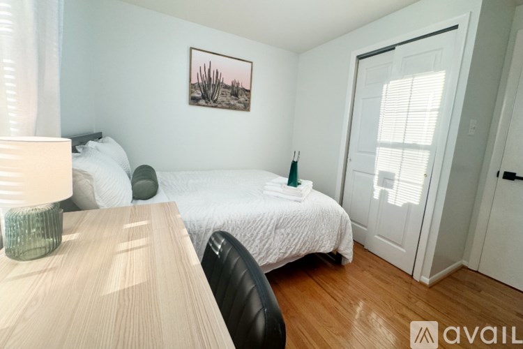A bedroom with a bed, a chair, and a painting on the wall.