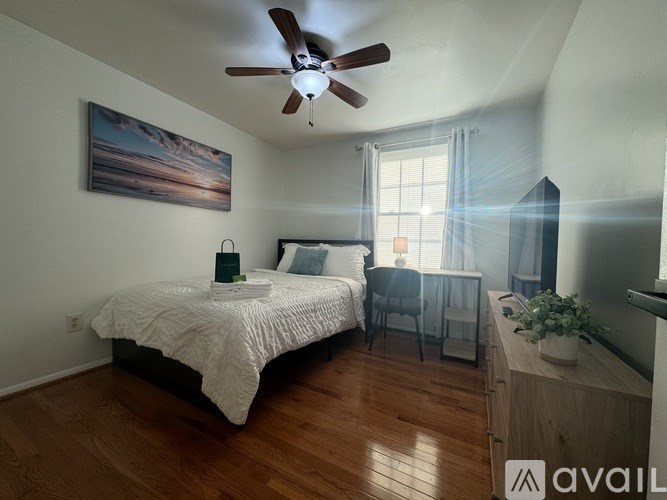 A bedroom with a bed, a chair, a table, and a painting on the wall.