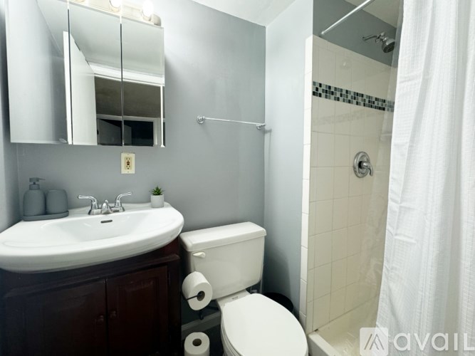 A bathroom with a white sink, toilet, and a shower with a white curtain.