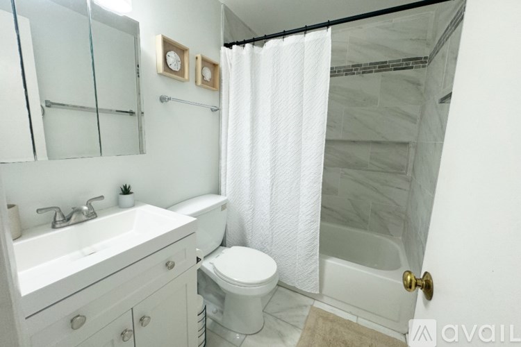 A white bathroom with a toilet, sink, and shower.