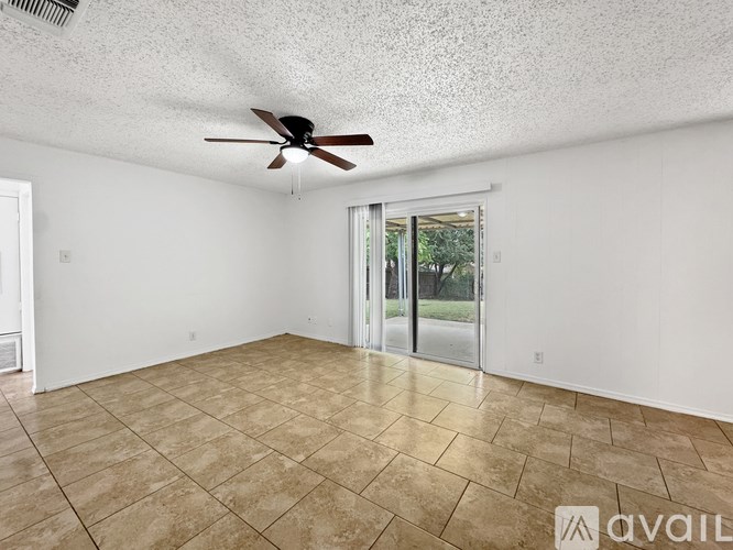 A room with a ceiling fan and sliding glass doors.