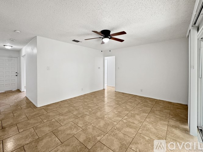 A room with a ceiling fan and tile flooring.
