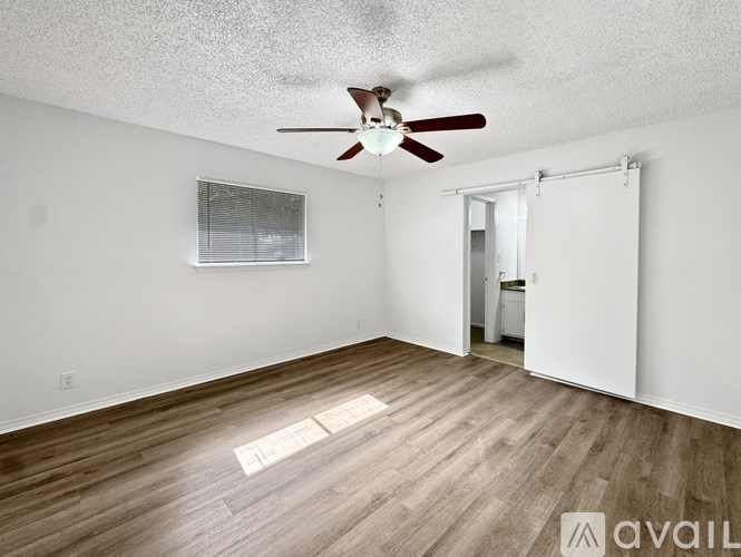 A room with a ceiling fan and wooden flooring.