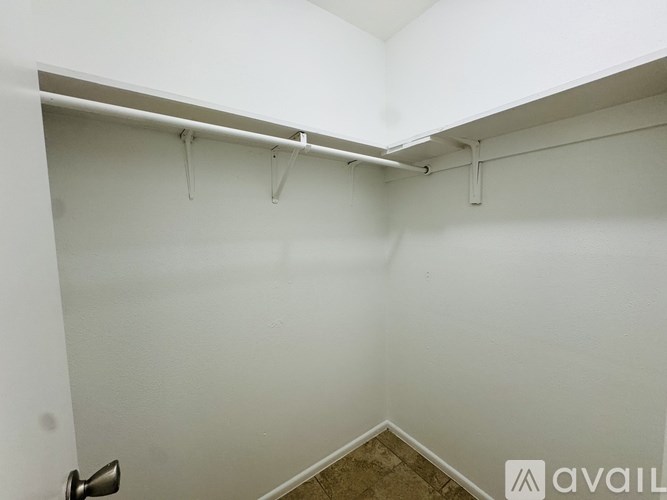 A white room with a door and a brown floor.