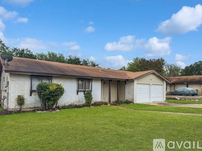 A house with a white exterior and a brown roof is surrounded by a green lawn.