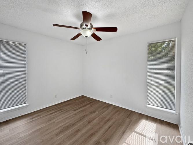 A room with a ceiling fan and wooden flooring.