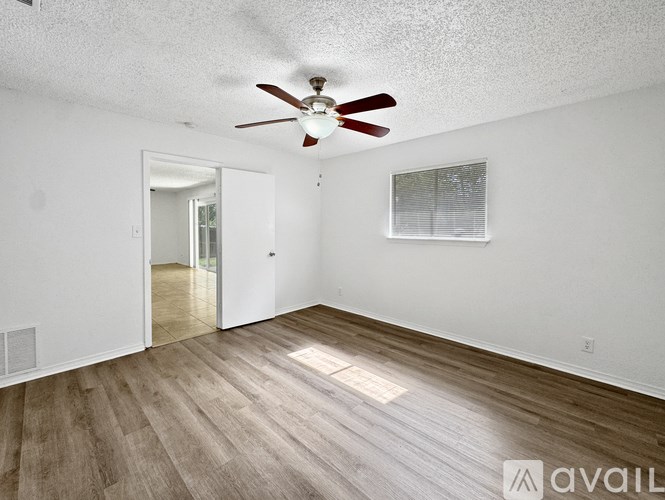 A room with a ceiling fan and wooden flooring.