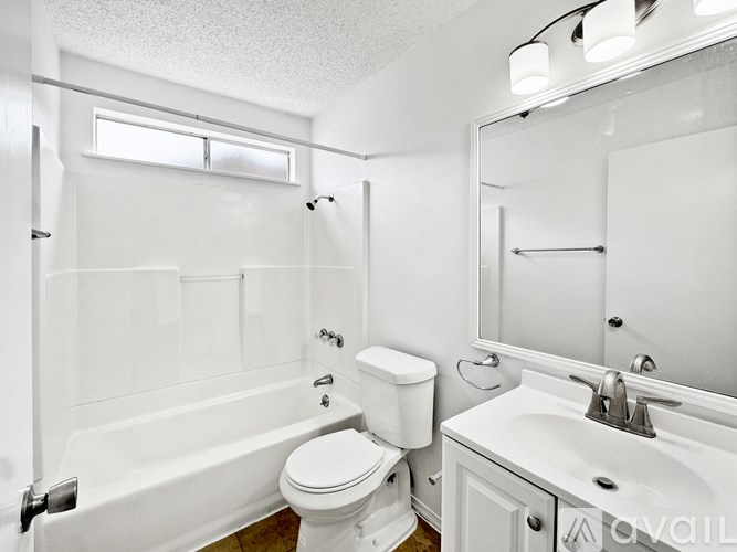 A white bathroom with a toilet, sink, and bathtub.