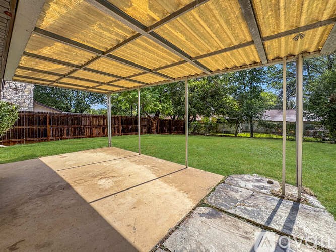 A covered patio area with a concrete floor and a wooden ceiling.
