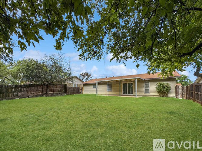 A house with a fence and a tree in the foreground.
