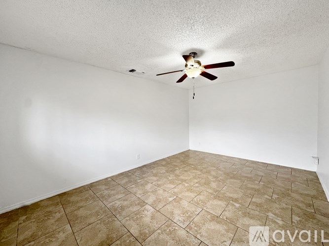Empty room with a ceiling fan and tiled floor.