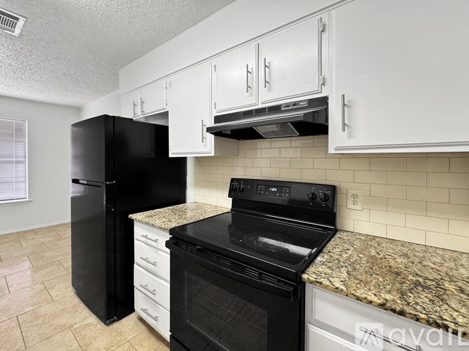 A kitchen with black appliances and white cabinets.