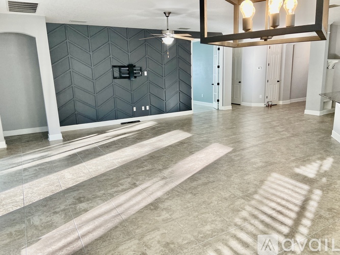 A spacious room with a tiled floor and a ceiling fan.