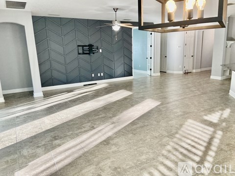 A spacious room with a tiled floor and a ceiling fan.