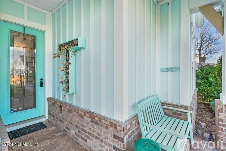 A blue and white striped house with a green chair in front.