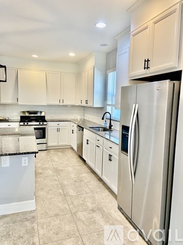 A kitchen with white cabinets and a stainless steel refrigerator.