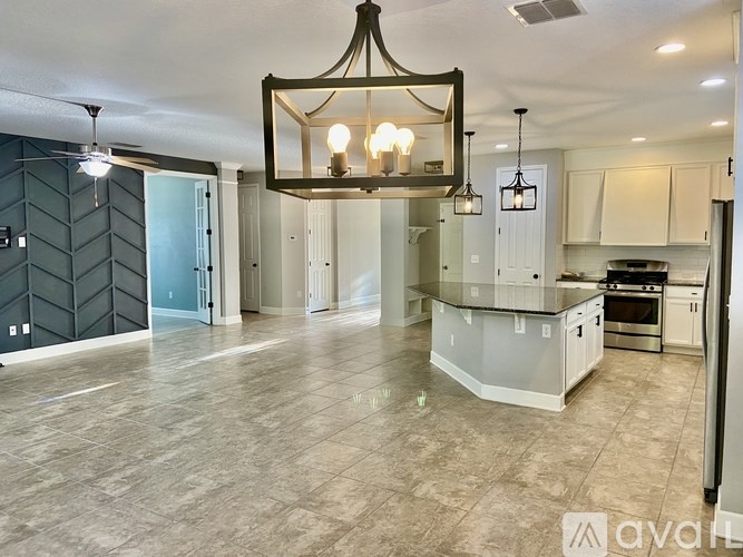 A large, empty kitchen with a chandelier hanging from the ceiling.